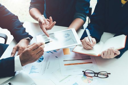 Stock photo of three people sitting around a table consulting on a project.