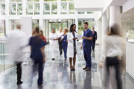 Stock photo of busy hospital staff walking through a hallway.